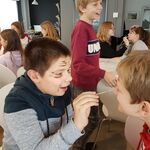 Uczeń trzyma w ręku pędzelek i maluje twarz drugiemu.
