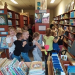 Uczniowie ida gęsiego między półkami z książkami.
