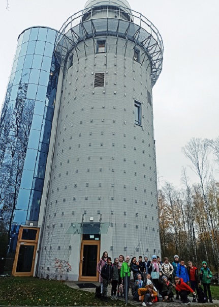 Grupa uczniów stoi na tle wysokiej wieży