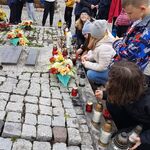 313Uczniowie palą znicze w rękach przed grobem  żołnierzy.