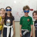 Czterech uczniów stoi w klasie, dwoje ma założone ciemne okulary