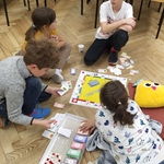 Czterech ucnziów gra w planszówki na podłodze.