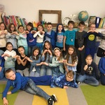 Grupa uczniów w klasie ubranych na niebiesko, robi z dłoni serduszka.