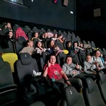 Uczniowie siedzą w fotelach kinowych.