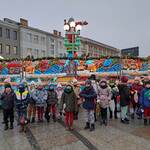 Grupa dzieci stoi na rynku przed świąteczna karuzelą.
