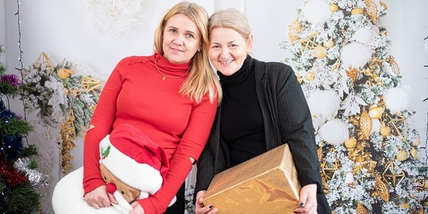 Dwie kobiety stojące obok siebie na tle świątecznego wystroju.