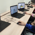 Uczniowie siedzący w sali przed laptopami i wykonujący projekty