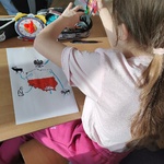 Dziewczynka rysuje plakat na ławce.