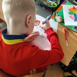 Chłopiec rysuje kontur Polski  na ławce w klasie.