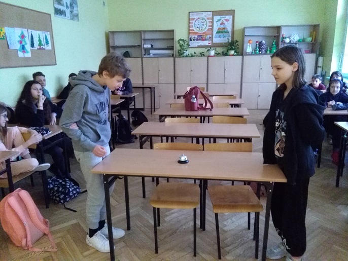 Uczeń i uczennica stoją przy stole na przeciw siebie