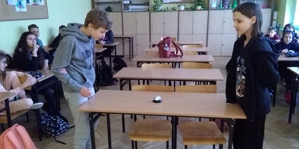 Uczeń i uczennica stoją przy stole na przeciw siebie