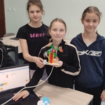 Czworo uczniów stoi obok laptopa . Dwie dziewczynki trzymają w rękach budowę z klocków lego..jpg