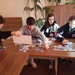 Uczniowie i uczennice układają na stole duże puzzle - banknoty.