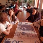 Uczennice siedzą przy stole na którym leży duży banknot 50 złotych.