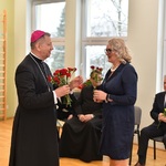 Arcybiskup wręcza kwiaty pani wicedyrektor.