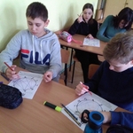 Dwóch uczeniów wykonuje kartę pracy siedząc w ławce.