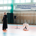Misjonarz przemawia do uczniów na hali sportowej.