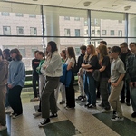 Grupa uczniów stoi na korytarzu z dużą szklaną ścianą..jpg