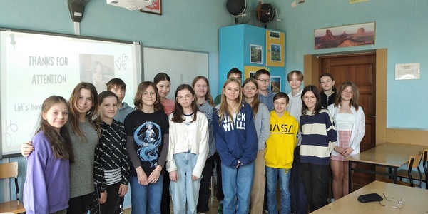 Grupa uczniów stojąca w klasie przy tablicy multimedialnej.
