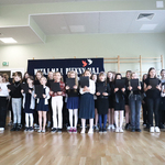 Duża grupa uczniów ubrana na galowo śpiewa piosenki