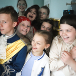 Grupa uczniów zagląda przez drzwi i śmieje się.