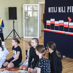 Sześcioro uczennic siedzi na podłodze, obok stoi chłopiec przebrany za króla.