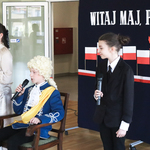 Dwie dziewczynki stoją z mikrofonami, na fotelu pomiędzy nimi siedzi przebrany za króla chłopiec.