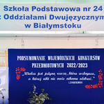 Dwa duże napisy, jeden na niebieskim tle, obok przemawia kobieta.