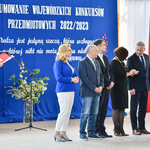 Dorosłe osoby - dyrektorzy- stoją na tle tle napisów na niebieskim płótnie.