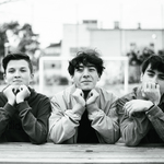 Czarno-białe zdjęcie trójki uczniów opierających się na dłoniach.