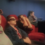 Uczniowie siedzą w ciemnych okularach na czerwonych fotelach.jpg