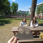 Dwie dziewczynki siedzą przy drewnianym stoliku na placu szkolnym_ na pierwszym planie zdjęcie czarno-białe..jpg