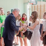 Pan dyrektor dostaje od uczennicy różę. Obok stoją uczniowie i nauczycielki.