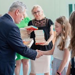 Pan dyrektor wręcza książki uczniom.