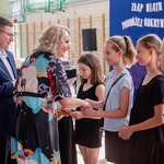 Pani dyrektor wraz z nauczycielem wręcza książki uczniom.