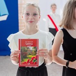 Uśmiechnięta uczennica trzyma książkę w ręku.