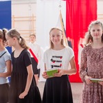 Uśmiechnięte uczennice stoją z książkami na sali.