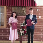 Elegancko ubrana kobieta trzyma w ręku dyplom_ obok niej stoi uczeń ubrany w garnitur z dyplomem i medalem w ręku..jpg