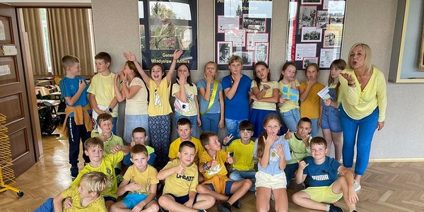 Na korytarzu szkolnym stoi grupa uczniów oraz nauczycielka ubrani w kolory żólto -niebieskie..jpg