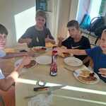 Czterech chłopakówi siedzi przy stole z talerzami pełnymi jedzenia..jpg