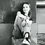 Dziewczyna siedzi przy murze.
