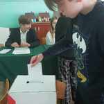 Chłopak wrzuca kartę do głosowania do urny