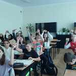Uśmiechnięci uczniowie w klasie trzymają w górze w rękach notesiki..jpg