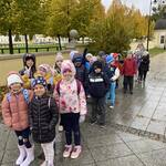 Grupa uczniów ciepło ubranych stoi na podwórku przy  jesiennych drzewach..jpg