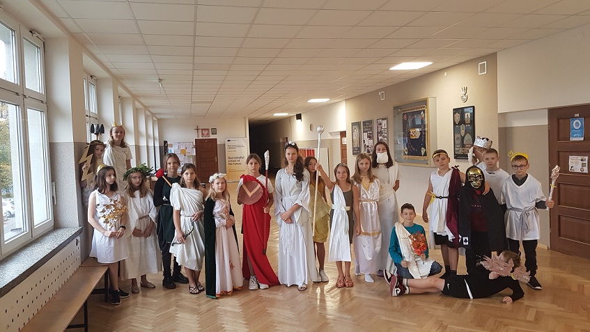 Grupa uczniów przebrana za greckich bogów stoi na korytarzu szkolnym..jpg