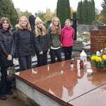 Grupa uczennic stoi przy pomniku na cmentarzu..jpg