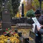 Uczennica czyta z kartki informacje przy grobie na cmentarzu..jpg