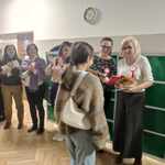 Uczennica odbiera ngrodę od nauczycielek stojących przy zielonych szafkach..jpg