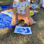 Na pierwszym tle siedzi uczeń na trawie i maluje rysunek_ za nim siedzi gupa dzieci z farabami..jpg