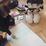 Grupa uczniów rysuje plakat siedząc na podłodze..jpg